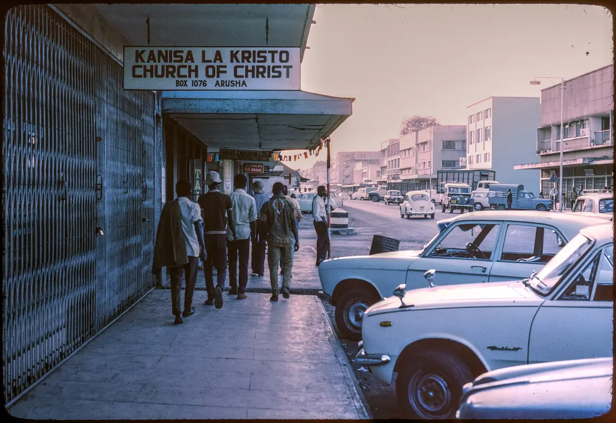 Historische Ansicht einer Einkaufsstraße in Arusha mit parkenden Autos im Jahr 1973